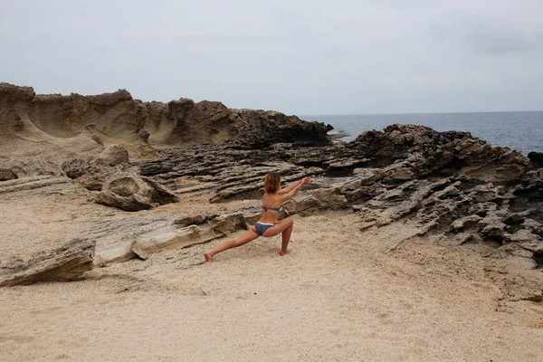 Woman doing yoga on the stone nearby sea — Stock Photo, Image