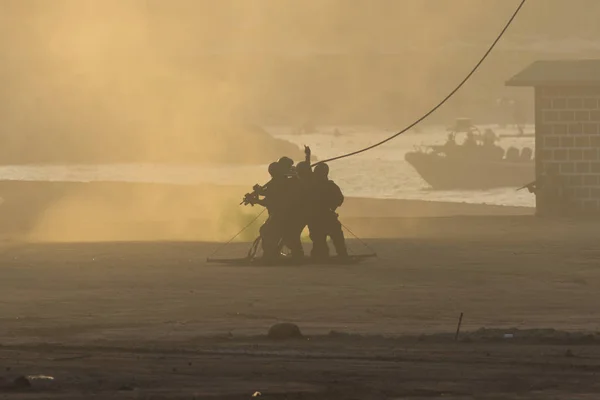 紛争の軍事チームはヘリコプターで人々を救う。中東紛争の煙と煙の中でチョッパーに接続されているロープにロードされます. — ストック写真