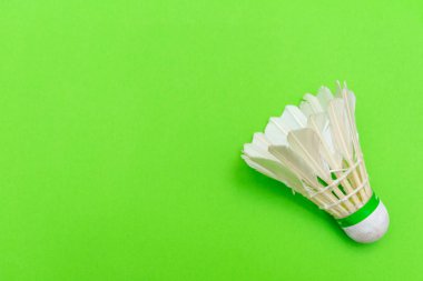 Badminton mekik ya da kuşçuğu, parlak yeşil düz bir arka planda uzanmış, kopyalama alanı ile spor ve aktiviteyi sembolize ediyor..