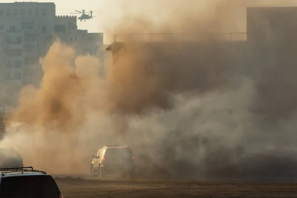 Askeri helikopter ve ordu araçları dumanın ve savaşın içine girip çıkıyorlar. Askeri güç kavramı, güç, güç, hava saldırısı, patlama. — Stok fotoğraf