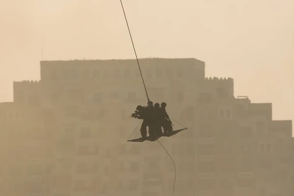 Vojenský tým v konfliktu zachraňující lidi vrtulníkem. létání vzduchem na laně připevněném k vrtulníku v kouři a oparu na Blízkém východě konfliktu. — Stock fotografie