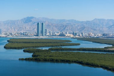 Dubai 'nin kuzeyindeki Ras al Khaimah, Birleşik Arap Emirlikleri' nin havadan görünüşü, şehri, Hajar dağlarını, Jebal Jais 'i ve Corniche boyunca uzanan Mangrovları izliyor..