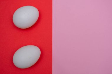 İki Paskalya bayramı dairesi, beyaz yumurtayla birlikte koyu kırmızı ve pembe pastel üzerine uzanır ve fotokopi alanı ile canlı bir arka plan oluşturur..