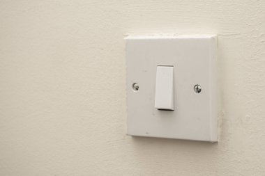 Beyaz bir duvarda basit beyaz bir elektrik düğmesi. Endüstriyel, konut veya Diy inşaat kavramları.
