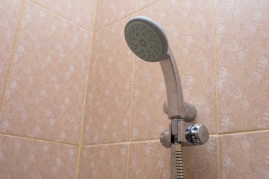 Banyoda duş başlığı var. Temizlik ve banyo için turuncu fayansları teslim ediyor. Tesisat, hijyen ve konutlar.
