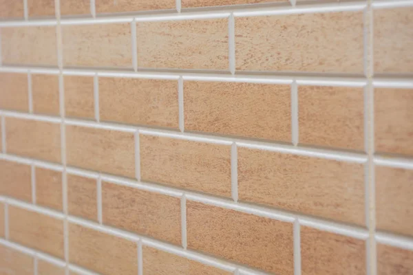 Angled view of Beige textured brick interior or exterior wall with white grout. A concept or background for interior design, construction, DIY, or building.