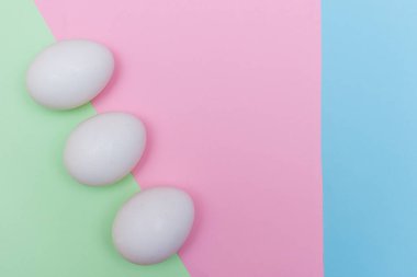 Üç Paskalya bayramı dairesi, açık yeşil, mavi ve pembe pastel arka planda beyaz yumurtayla yatıyordu..