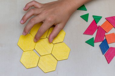 Tangram altıgen çiçek renkli çocuk geometrik yapboz parçası. Kahverengi arkaplan için son parça elle dolduruluyor..