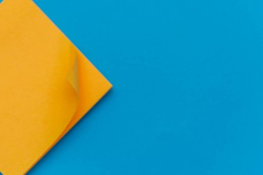 Açık mavi düz arka plan üzerine parlak turuncu not eğitim veya iş organizasyonu ve hatırlatıcı kavramlar için yatıyordu.