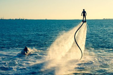 Güneş batarken Dubai yakınlarındaki Birleşik Arap Emirlikleri 'nde Ras al Khaimah' da jet ski ile uçan ve ekstrem su sporları yapan bir uçuş. Eğlence ve spor kavramları.