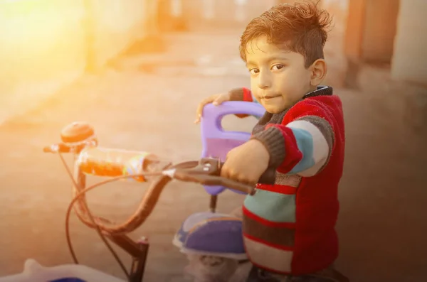 Poikalapsi polkupyörän kanssa auringon laskiessa — kuvapankkivalokuva