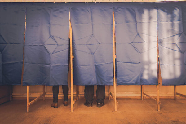 Люди голосуют в кабинке для голосования
