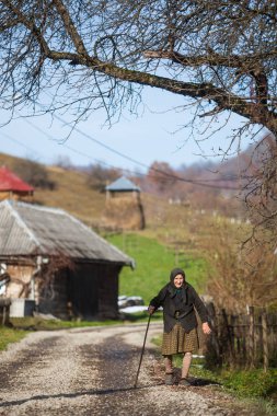Yaşlı kadın bir köyde bir caddede yürür