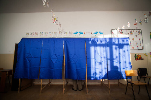 Люди голосуют в кабинке для голосования
