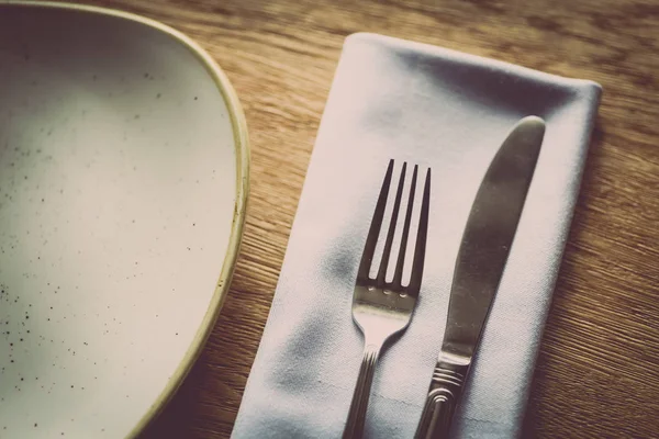 Tenedor y cuchillo en una mesa, cerca de un plato — Foto de Stock