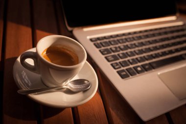 Yukarıdan bir fincan kahve ve bir dizüstü bilgisayar klavye ahşap bir masa üzerinde görüntü renk.