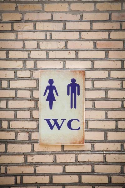 Color detail of a WC sign on a brick wall.