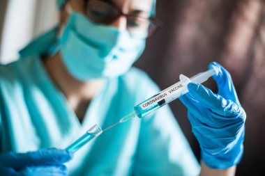 Coronavirus COVID-19 aşısıyla şırınga tutan bir hemşirenin kavramsal görüntüsü..