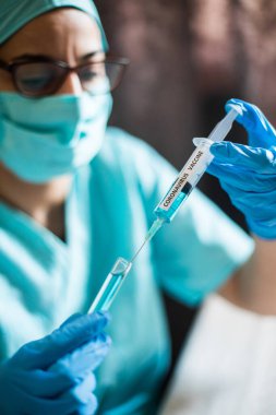 Coronavirus COVID-19 aşısıyla şırınga tutan bir hemşirenin kavramsal görüntüsü..