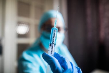 Coronavirus COVID-19 aşısıyla şırınga tutan bir hemşirenin kavramsal görüntüsü..