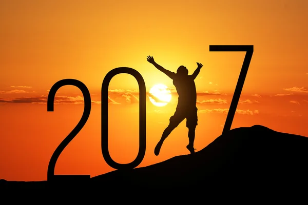 Silhouette person jumping over 2017 on the hill at sunset — Stock Photo, Image