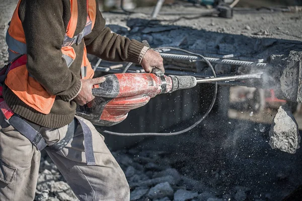 Um homem a usar uma marreta para perfurar a parede. trabalhador profissional no estaleiro de construção — Fotografia de Stock