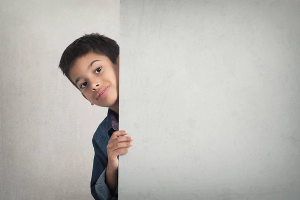 Lindo chico mirando desde detrás del tablero de publicidad en blanco — Foto de Stock
