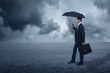şemsiye ayakta, bulutlu bir arka plan ile işadamı
