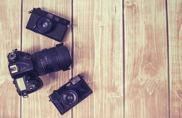 Três câmeras diferentes no desktop de madeira marrom — Fotografia de Stock