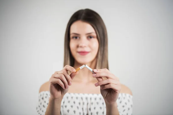 Close up retrato de jovem mulher atraente quebrando cigarro em pedaços. Estúdio tiro seletivo foco isolado em cinza. Conceito de dependência — Fotografia de Stock