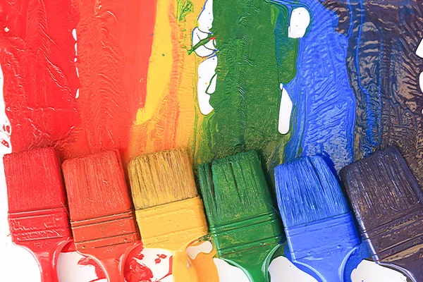 Um fundo de tinta colorida em diferentes pincéis — Fotografia de Stock