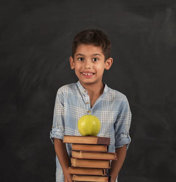 Nahaufnahme eines kleinen Jungen mit einem Stapel Bücher und Äpfeln. glücklicher Schuljunge lächelt und blickt in die Kamera. lizenzfreie Stockbilder