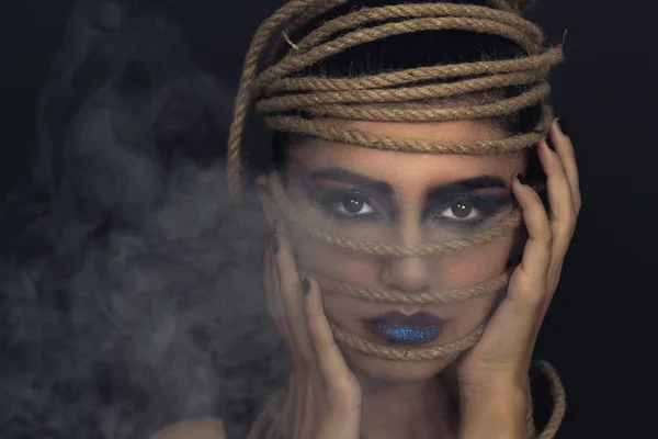 Портрет молодой женщины на веревке с черным фоном. Мода, необычный макияж и концепция лифтинга лица . — стоковое фото