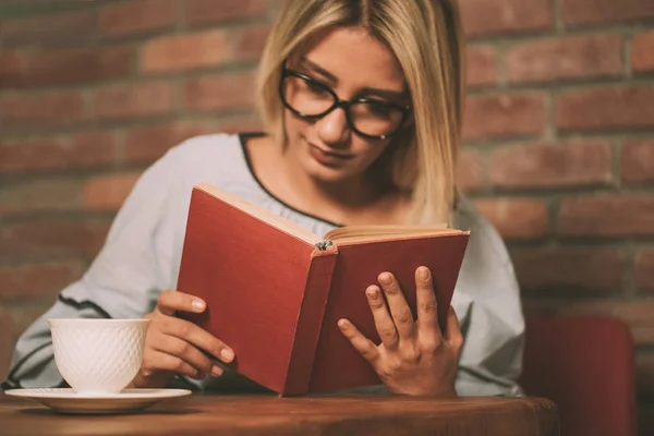 Mujer sentada en una mesa leyendo un libro —  Fotos de Stock