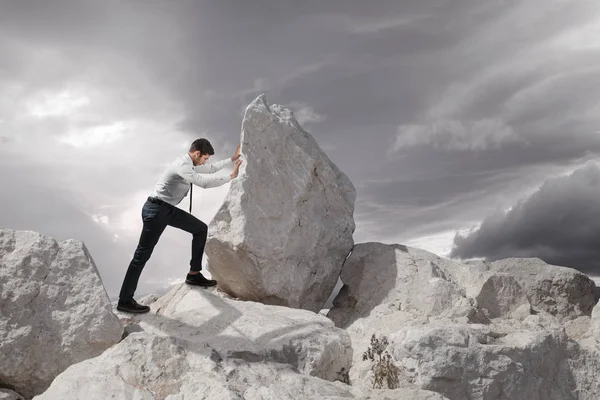 Business concept, Young businessman pushing large stone uphill with copy space — Stock Photo, Image