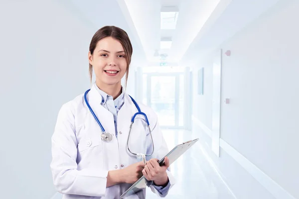 Mladá žena lékař stojící a usmívající se na nemocnici — Stock fotografie