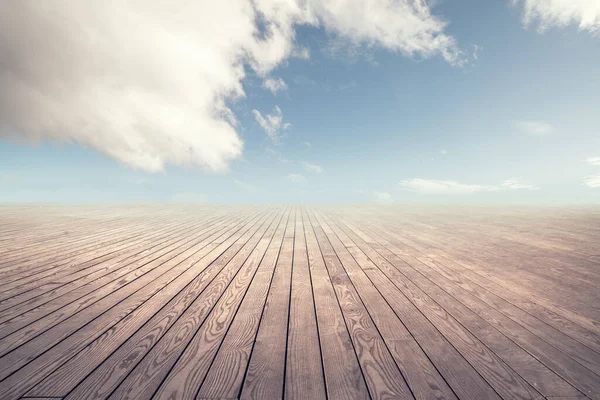 Empty wooden floor against cloudy sky with clouds.