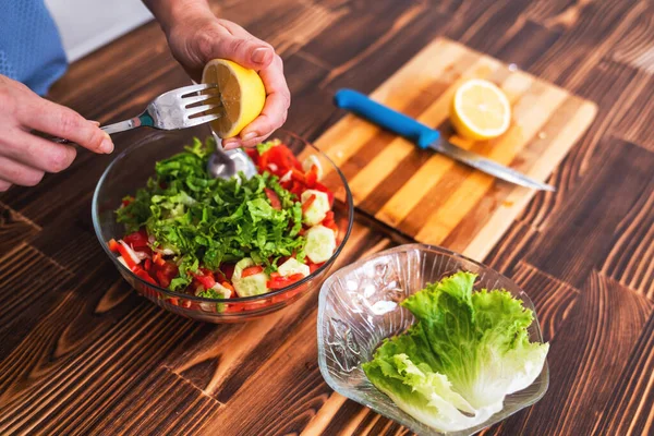 Young woman is squeezing lemon on cutting board for salad — Φωτογραφία Αρχείου