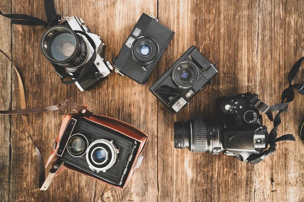 The evolution of the photo cameras on a wooden backraound. Camera technology concept. — Stock Photo, Image