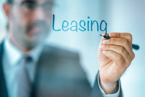 Businessman write the word Leasing and give a brief property, buildings, vehicles are common assets that are leased.