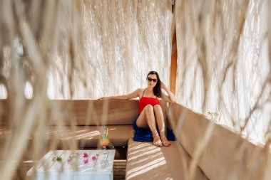 Genç bir kadın deniz kenarında tatilde içkisiyle rahatlıyor. 