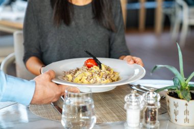 Genç bir kadın garsondan nefis bir fettuccine alıyor bir elagance restoranında öğle yemeğinde.