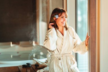 Güzel bir kadın spa merkezinde masaj beklerken pencereden dışarı bakıyor..