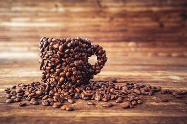 A cup covered with many coffee beans, strong coffee concept. — Stock Photo, Image