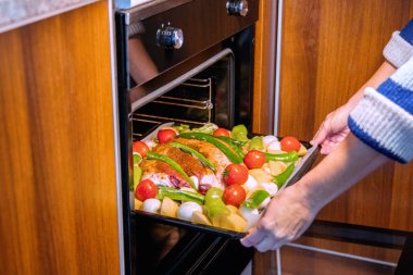 Mutfakta lezzetli bir yemek hazırlamak ve özel bir akşam yemeği için tepsiyi kızartma makinesine koymak..