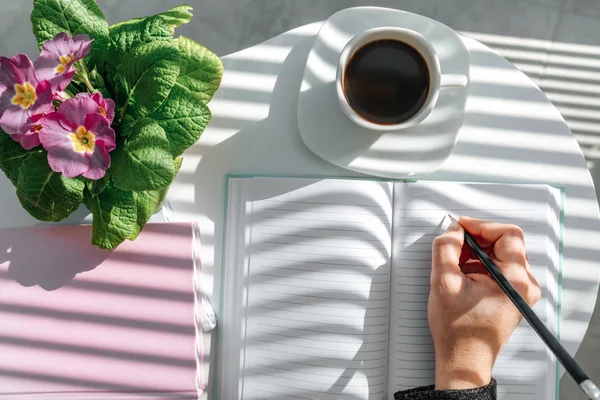 Hand writing with a pencil in open notebook on white table. Bird eye view, mock-up concept. — 스톡 사진