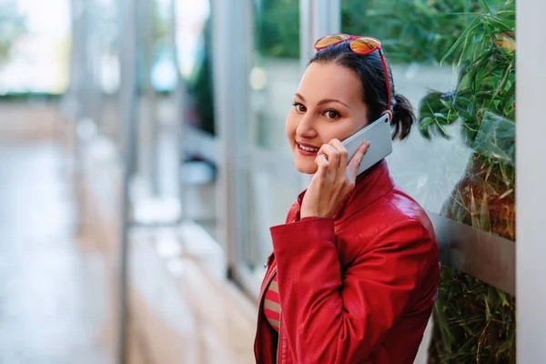 Söt ung kvinna står och talar med mobiltelefon med ett glatt leende. — Stockfoto