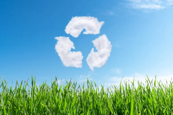 Wolken am blauen Himmel in Form des Symbols des Recyclings auf grünem Hintergrund. Naturschutz und Zukunftskonzept. — Stockfoto