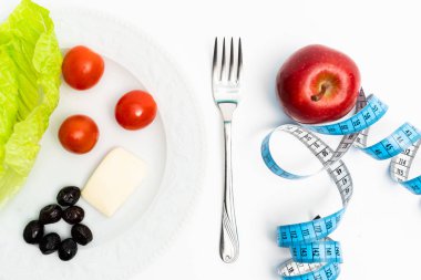 İzole edilmiş kırmızı elma ve beyaz arka planda şeritle ölçülen sağlıklı yemek tabağı. Diyet ve sağlıklı yaşam konsepti.