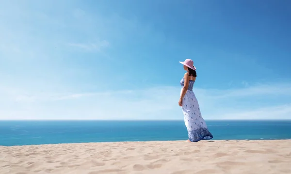 Side view of beautiful woman in a dress enjoying the idyllic scene of the sun, sand and sea. Beautyful sandy Patara beach in Antalya.